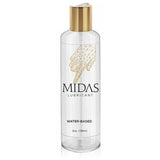 A clear plastic bottle of the gold standard Midas Water Based Lube features a gold cap, with a label showing a geometric hand design pointing down and text: MIDAS Lubricant, WATER-BASED, and 4 oz. (118 ml).