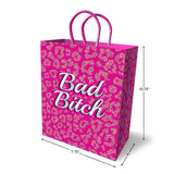 The Bad Bitch Gift Bag, a novelty gift bag in durable pink card stock, boasts a bold leopard print and purple braided handles. Bad Bitch appears in white stylized text. Ideal for gifting, it measures 10.75 tall, 7.75 wide, and 4 deep.