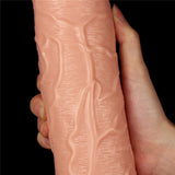 A hand holds the King Size 11 Realistic Dildo - Flesh 28 cm Dong, featuring a pinkish hue with prominent vein-like patterns and a suction cup base. Ridges and grooves emulate intricate skin details, highlighted against a solid black background.