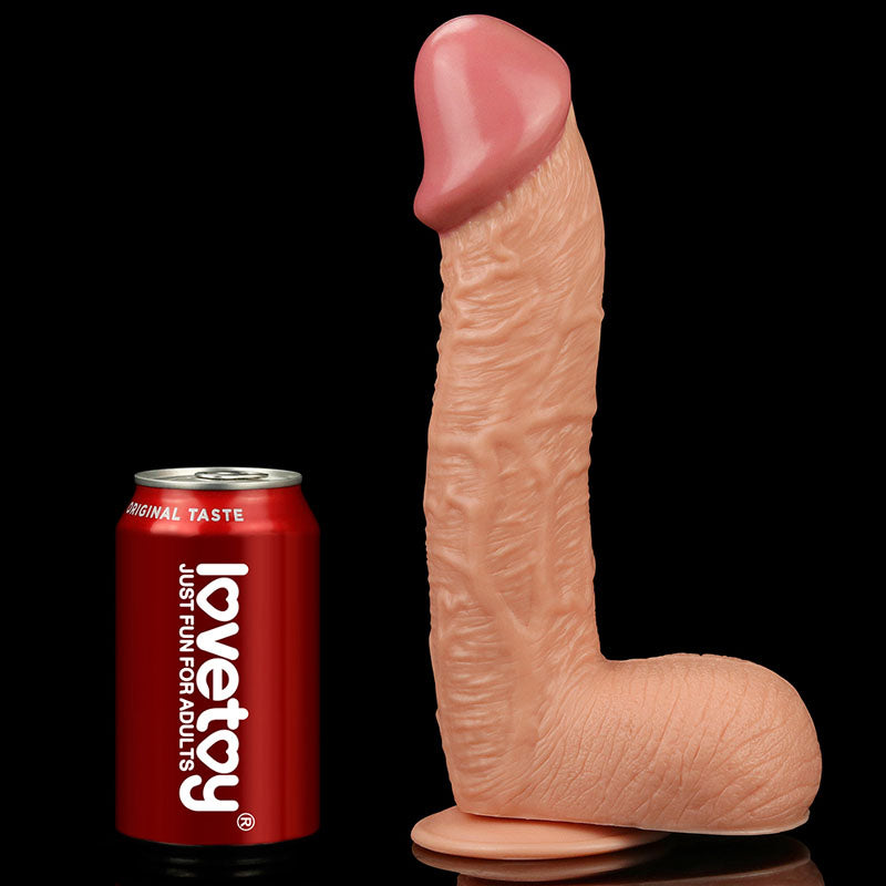 A realistic King Size 10.5 flesh-toned dildo with a veined texture stands on its suction cup base. Next to it, a red lovetoy soda can denotes size for comparison, set against a black background to highlight the impressive craftsmanship of this 26.7 cm dong.