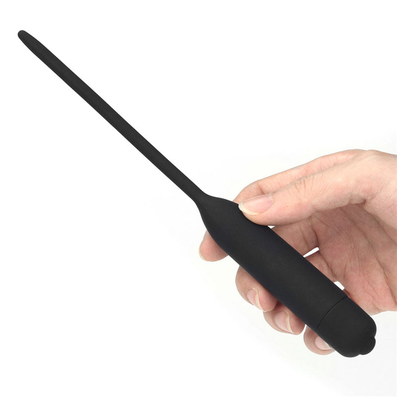 A hand holds the Ultimate Silicone Vibrating Urethral Dilator, showcasing its sleek black design with a smooth matte finish and tapered tip. The white background highlights this intriguing Black Vibrating Urethral Sounds elegant form in the persons hand.