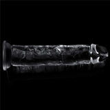 The Flawless Clear Dildo from the LOVETOY Shameless Clear Series, a 7-inch clear dong, appears as a cylindrical rod with a rounded end on a black reflective surface. Its intricate internal patterns catch the light, emphasizing its transparent and textured design against the dark background.