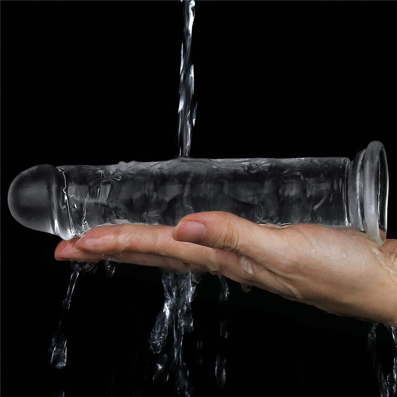 A hand holds the skin-safe Flawless Clear Dildo 7 from LOVETOY, letting water cascade over it against a black backdrop, highlighting its sleek, cylindrical design with rounded ends.