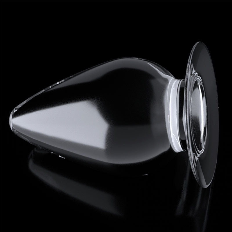 The Flawless Clear Anal Plug 4.5 showcases its sleek, transparent design against a black background, featuring a skin-safe, bulbous shape and wide flared base, with its reflective surface enhancing the subtle highlights and shadows.