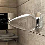 A metallic object, like a futuristic door handle, adorns a neutral wall with a blurred mirror reflection above a modern sink. This sleek setting mirrors the sophistication and style of the Flawless Clear Anal Plug 4.5, blending elegance effortlessly.