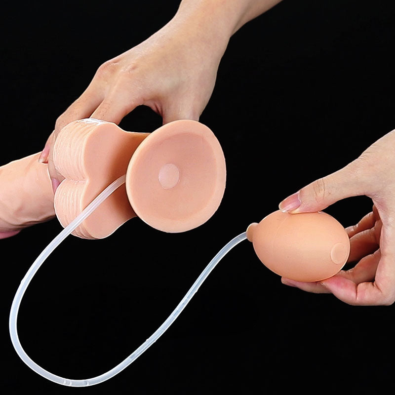 Hands hold a beige Cumming Softee 9 with lifelike features, ribbed sides, and a round base. A thin tube connects to an oval hand pump. The solid black background highlights the structure and texture of the 22.9 cm Flesh Squirting Dong.