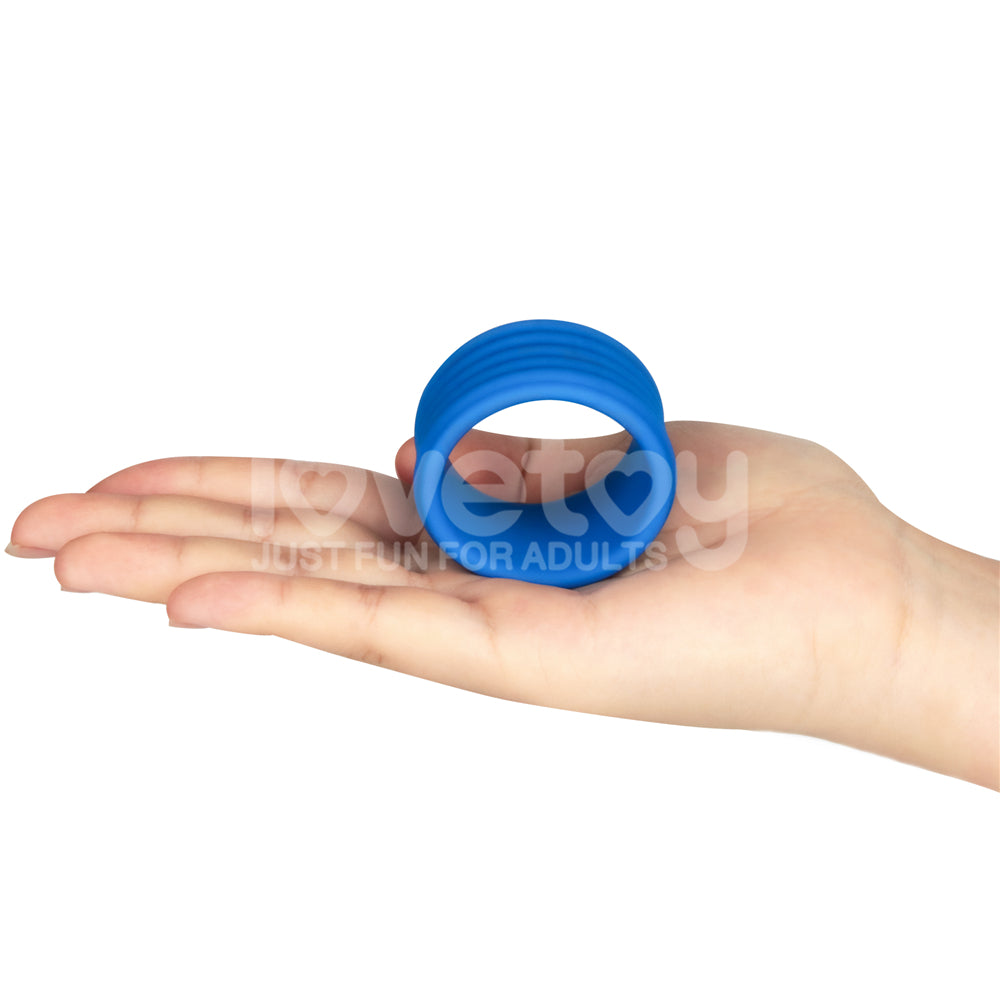 A blue Pinnacle Pro Deep Rib Grip - Blue Cock Ring rests in the center of an outstretched light-skinned hand, its texture and color highlighted against a plain white background. The words I love toy, just fun for adults are faintly visible over the rings firm grip.