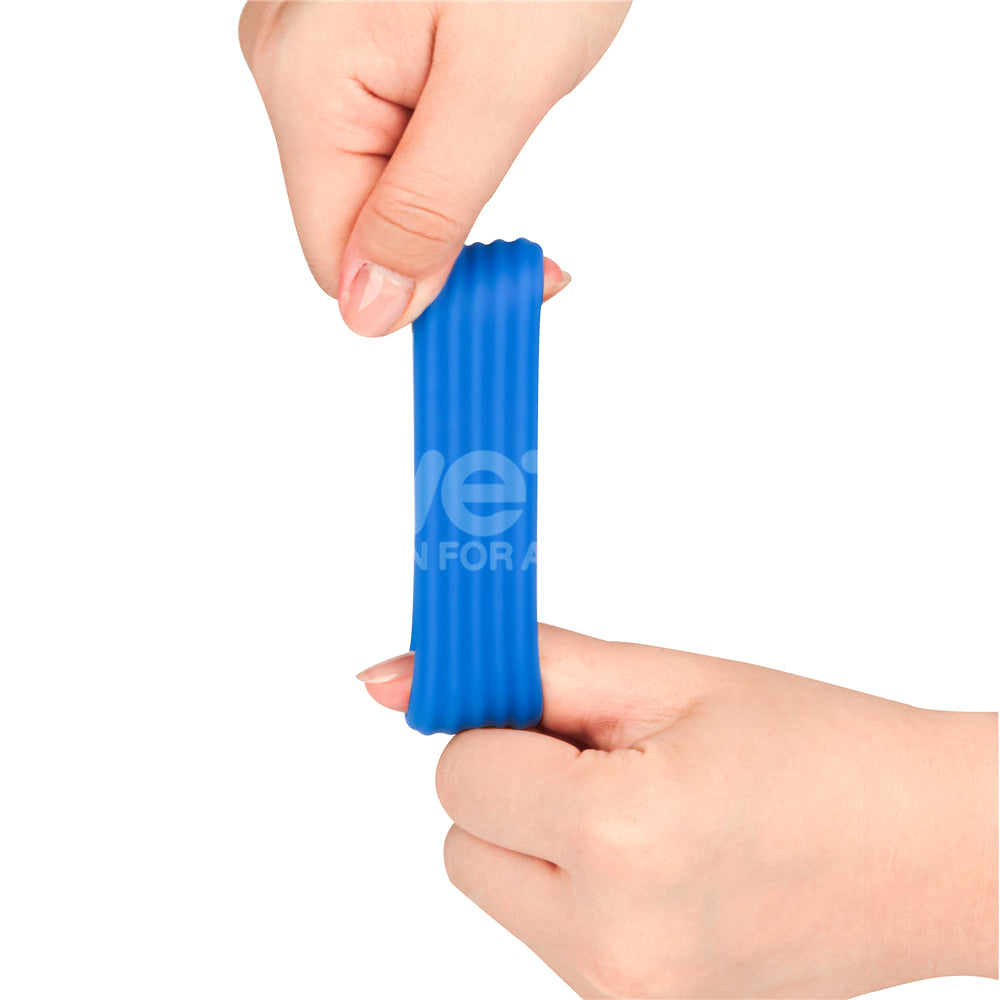 Two hands firmly grip a Pinnacle Pro Deep Rib Grip - Blue Cock Ring, stretching the blue, ribbed silicone horizontally. Against the white background, the vibrant blue hue and textured ribs of the ring stand out as they pull slightly apart.