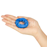 A hand holds the Pinnacle Pro Ridge Bump Stretcher, a small blue silicone cock ring with a textured surface for enhanced stimulation. Its slightly stretchy, set against a plain white background with faint watermarks.