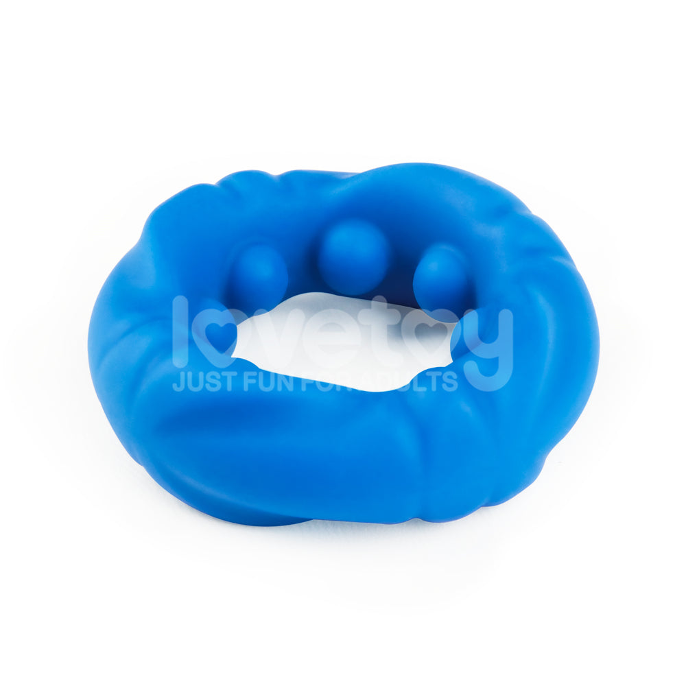 The Pinnacle Pro Ridge Bump Stretcher is a blue silicone cock ring with a textured surface and multiple round bulges for added stimulation. Its slightly misshapen and irregular, with the faint text lovetoy just fun for adults visible on the ring.