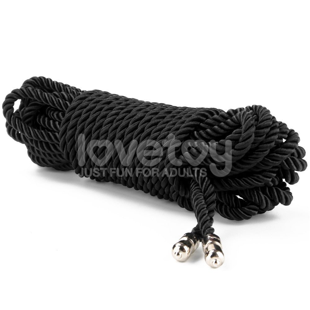 The Rebellion Reign Silky Bondage Rope, a sleek black 10-meter coiled rope with metal-tipped ends, elegantly rests against a white backdrop. Made from premium polyester, it subtly features lovetoy and JUST FUN FOR ADULTS across its surface.