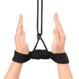 Two hands are tied with Rebellion Reign Silky Bondage Rope in black, palms facing inward. The fingers are extended with neat nails. Premium polyester loops above the wrists extend upward. The white background contrasts starkly with the black ropes ebony hue.