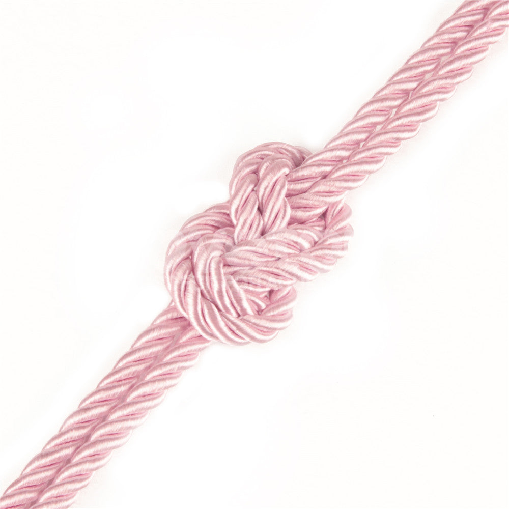 A detailed view of the Rebellion Reign Silky Bondage Rope in pink shows a neatly tied knot on a white background. Made of twisted strands, it has a strong textured surface with an intricate bondage design and a glossy, silky finish. The rope measures 10 meters in length.