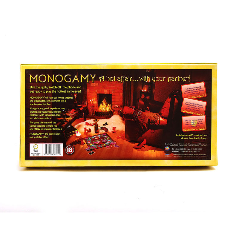 The back of the Monogamy - Adult Board Game box depicts an inviting scene: a dimly-lit living room, Monogamy game set up on the floor with red cards, wine glasses, and a cozy roaring fireplace promising an erotic fantasy with your partner.