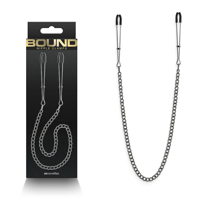 The image features Bound Nipple Clamps - DC3, crafted from gunmetal and adorned with rubber tips, linked by a chain for enhanced erotic sensations. Displayed beside its elegant packaging, the black box has gold and white text proclaiming BOUND NIPPLE CLAMPS, with the chain elegantly arranged.