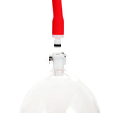 Close-up of the LuvPump Vagina Enhancement System, featuring a transparent polycarbonate container with a white valve, and a red-ended tube poised to connect. Faint markings are visible on the clear exterior.