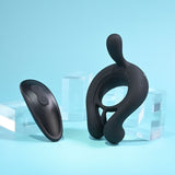 Displayed on a blue background, the Playboy Pleasure TRIPLE PLAY is a sleek black cock ring with a modern design and silicone construction featuring vibrating motors. An accompanying wireless remote, embossed with a Wi-Fi symbol, is surrounded by transparent acrylic blocks.