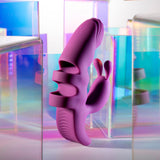 The Playboy Pleasure LEND A HAND - Purple USB Rechargeable Finger Vibrator, crafted from body-safe silicone with textured ridges and a smooth finish, is surrounded by transparent prisms that reflect rainbow hues, creating a vibrant atmosphere.