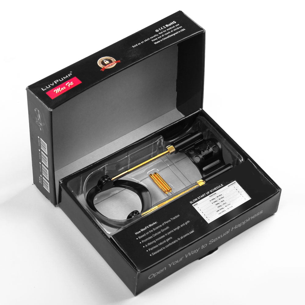 A black box with text, logos, and a chart on the lid and side reveals the LuvPump Max Fit Hybrid Penis Extender in gold and black. The extender has a tube-like attachment resembling a sleek design. The components are nestled in a transparent plastic insert against a white background.