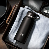 A sleek PDX Plus Fap Flask - Thrill Seeker - Frosted Discreet Stroker sits atop light blue jeans in a drawer, beside a grey towel and black goggles, showcasing a neatly organized space.