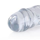 A close-up of the REALROCK 45 cm Double Dong showcases its transparent, cylindrical glass design with rounded ends. The glossy surface reflects light like crystal while resting on a white background, hinting at finger-like precision and highlighting its polished finish.