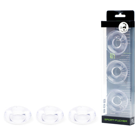 The image showcases a packaged set of three clear Sport Fucker Rubber Cockrings made from Thermo Plastic Rubber. The Monster TPR Donuts are vertically stacked in transparent packaging, with three extra loose rings displayed at the front to highlight their shape and clarity.