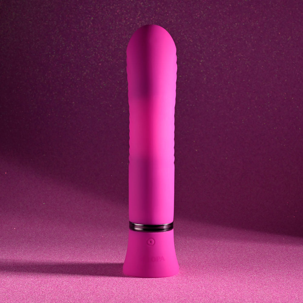 The Selopa NEXT WAVE - Pink 16.4 cm USB Rechargeable Dual Vibrator stands upright against a glittery pink background, featuring dual motors and a sleek cylindrical shape with a tapered tip. It has a wider base with an on/off symbol, soft silicone-like waterproof material, offering modern discretion.