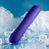 Standing against a blue backdrop, the Selopa AMBITION - Purple 17 cm USB Rechargeable Thrusting Vibrator, crafted from phthalate-free silicone with a ribbed cylindrical shape and rounded tip, contrasts its multi-speed design with scattered ice cubes and bears the engraved word VELORE near the top.