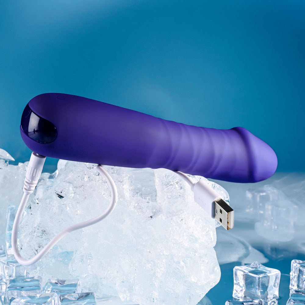 The Selopa AMBITION, a 17 cm purple USB rechargeable thrusting vibrator with a curved, bulbous end, rests on clear ice blocks. The backgrounds smooth gradient of light and dark blue enhances the icy theme.