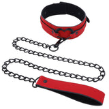 The Sex & Mischief Amor Collar and Leash - Red Restraint, made of vegan leather, features a heart-shaped buckle and a matching red and black chain leash. The shiny links enhance the collars heart theme, while the leash handle echoes its vibrant design.