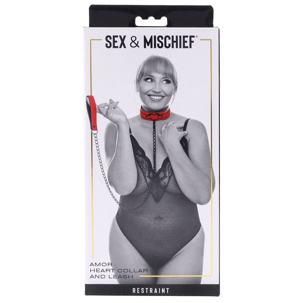 The packaging for Sex & Mischief Amor Collar and Leash - Red Restraint features a woman in lingerie wearing a vegan leather Amor Collar with a chain leash, smiling as she holds the leash. The white background text reads Amor Heart Collar and Leash and Restraint.