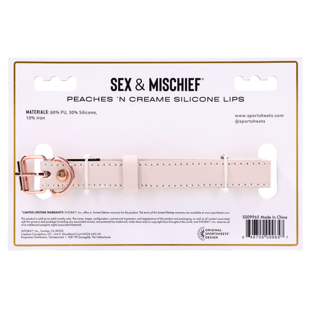 The packaging for the Sex & Mischief Peaches n CreaMe Silicone Lips - Peach Mouth Restraint features a faux leather strap with a rose gold buckle, designed for intimate moments. It also includes materials and warranty details, with brand info subtly placed at the bottom right.