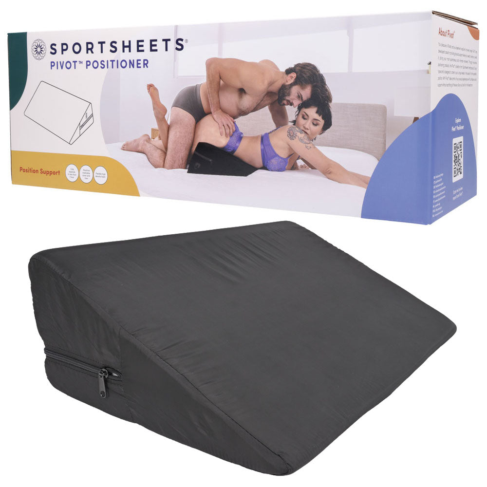 The Pivot Positioner - Black Foam Position Cushion, designed for superior positioning and support with high-density foam, features a zipper. The packaging shows a couple using it on a bed and includes the Sportsheets brand name, QR code, and illustrations.