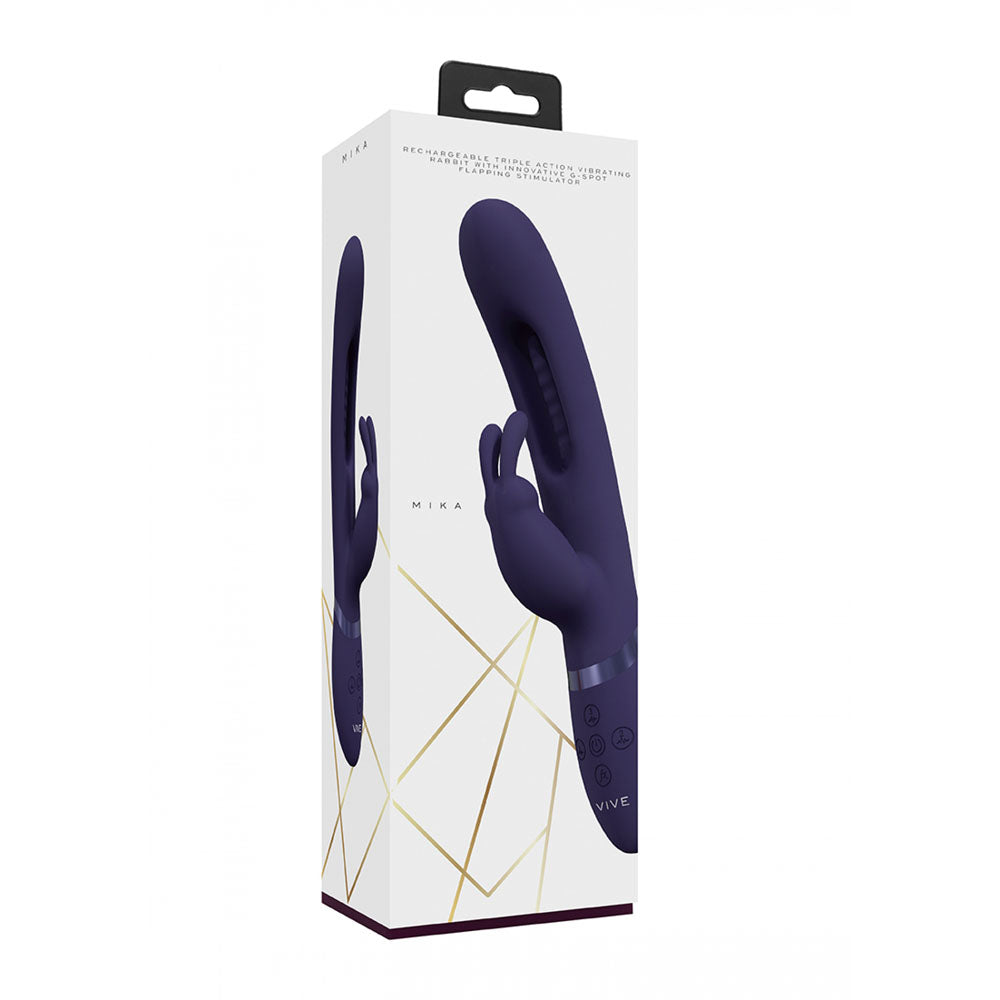 The image shows a rectangular box with the VIVE Mika Purple Rabbit Vibrator, featuring a flapping shaft in medical-grade silicone for dual stimulation. It stands vertically, adorned with geometric gold lines at the bottom and a black hanging tab on top.