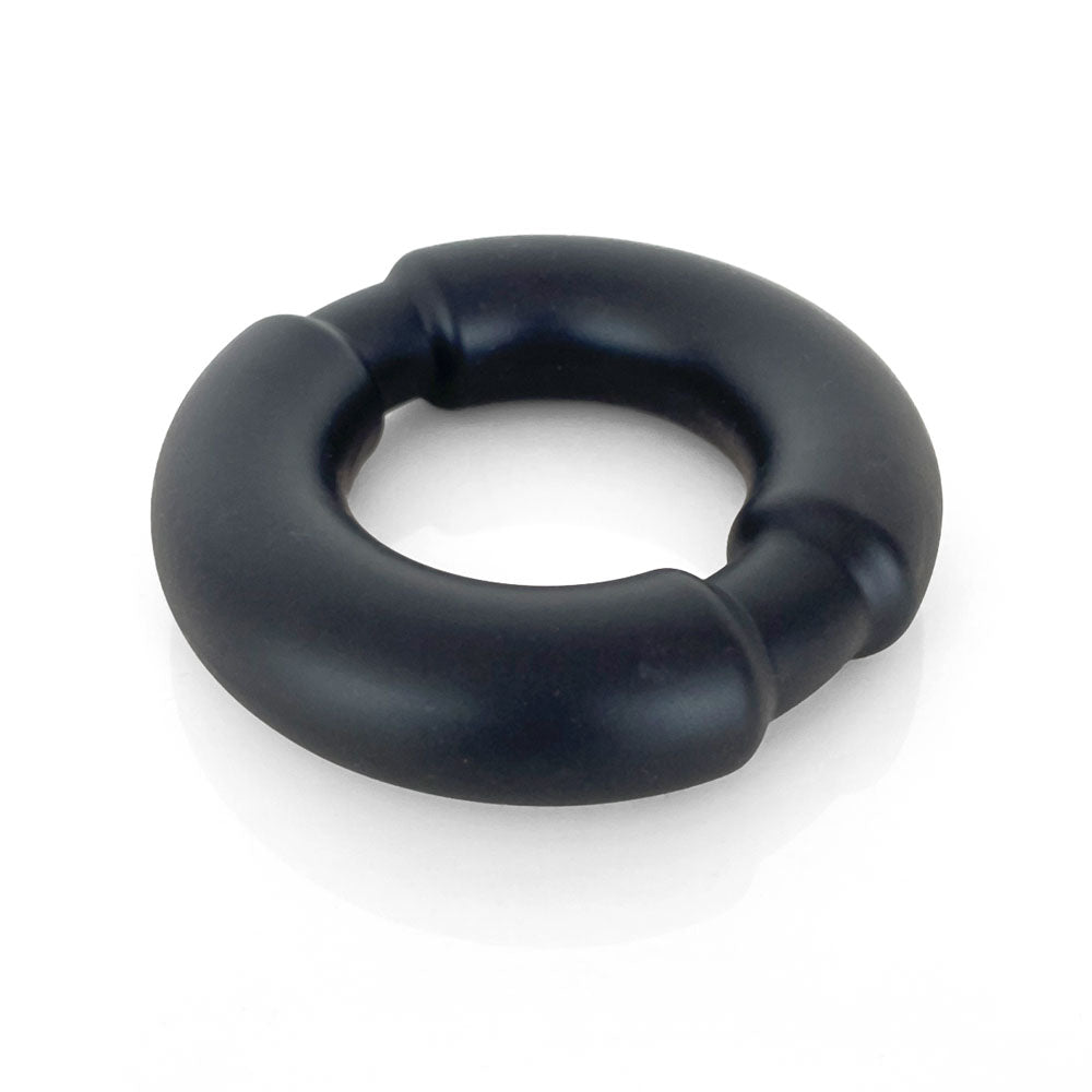 The VERS Liquid Silicone Weighted Steel Core C-Ring is a black, doughnut-shaped cock ring with a sleek matte finish and subtle ridges. Made of soft, flexible liquid silicone and featuring a steel core, it casts a light shadow on the flat surface beneath it.