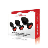 Introducing the WhipSmart Heartbreaker 3PC Silicone Crystal Heart Anal Training Set, featuring black butt plugs with red heart gem bases in sizes 2.75, 3, and 3.5. The box is adorned with elegant white and subtle red heart patterns for body exploration.