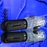 The Zero Tolerance THRILL RIDE, a clear textured flashlight-like device with a black handle, sits on a reflective surface against a vivid blue background. Its handle, which looks like a spinning stroker, showcases circular buttons and embossed arrow patterns with visible tubes and mechanics.