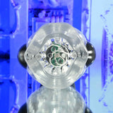 Close-up of the Zero Tolerance THRILL RIDE, a clear USB rechargeable thrusting, rotating, and vibrating stroker. Its transparent, faceted design features green circular patterns in motion. Set against a blue-toned abstract background, it exudes a futuristic ambiance with reflective surfaces below.