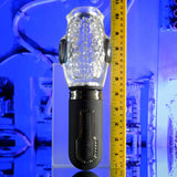 The Zero Tolerance THRILL RIDE, a futuristic transparent stroker with textured surfaces and black accents, stands vertically next to a yellow measuring tape against a blue-lit sci-fi background. The tape measures the products height at approximately 9 to 10 inches.