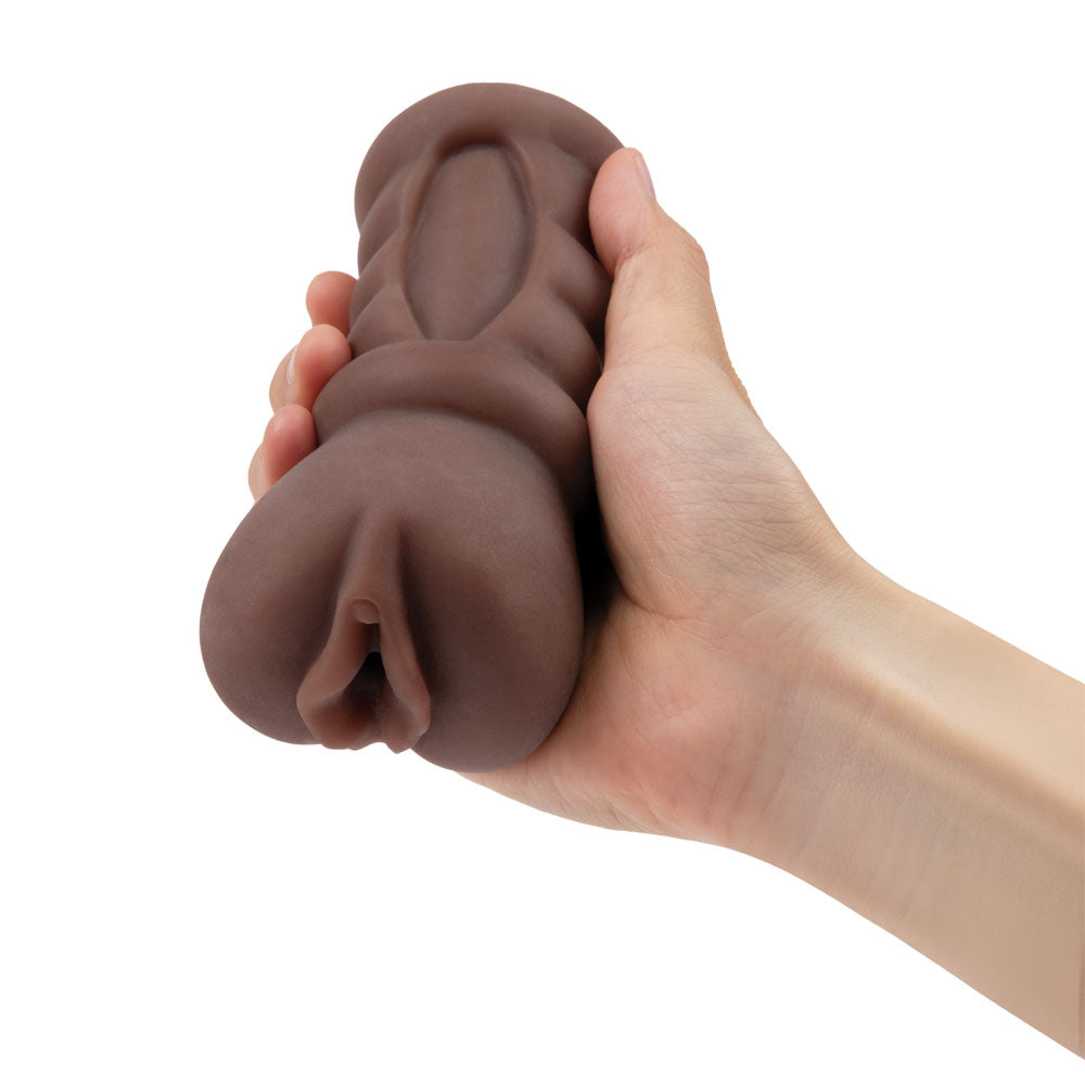 A hand holds a brown silicone personal massager, reminiscent of lifelike skin tone. Its contoured and flexible. The Zolo Stroke Off Diva Pussy Stroker - Brown Vagina Stroker is held upright, showcasing its grip-friendly design.