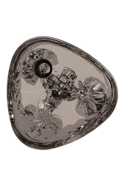 The Adam & Eve Adams 3-Way Stroker features a clear, triangular design with intricate floral patterns and an easy-grip exterior. The bottom has three raised flowers surrounded by embossed leaves, while its smooth, reflective glass surface adds subtle shadows and highlights.